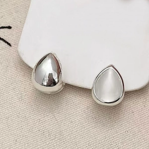 Detailed view of teardrop earrings with polished silver finish and white cat-eye stone