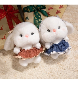 Close-up of plush rabbits in knit dresses against festive Christmas gift boxes