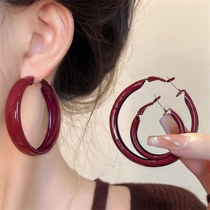 Macro detail of glossy dark burgundy C-shaped hoop earrings with vintage metal texture
