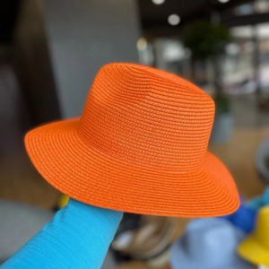 Detailed texture of bright orange woven straw sun hat with a wide brim for vacation