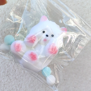 Soft white squishy cat toy with pink details in a zipper bag on plush background