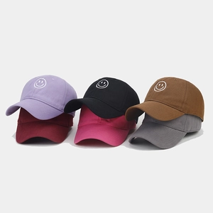 Detailed view of six colored cotton baseball caps with embroidered smiley face designs