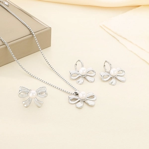 Close-up of silver bow jewelry set featuring white pearls on necklaces and earrings