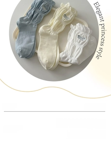 Detail of grey ruffled crew socks with bow and letter embroidery in a display tray