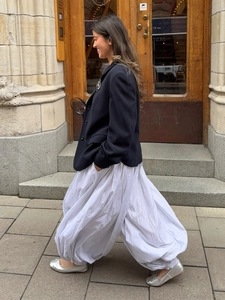 Close-up of baggy striped lantern trousers paired with a black blazer and silver shoes