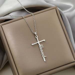 Macro shot of silver stainless steel cross pendant with blessed cursive lettering detail