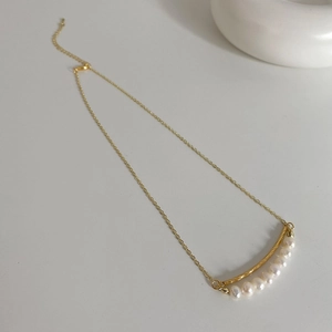Detailed view of a double-layered baroque pearl necklace with a twisted gold-plated bar