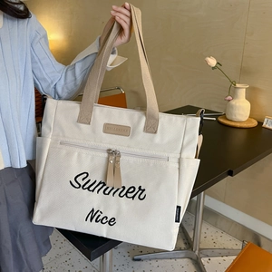 Close-up of cream canvas tote bag featuring Summer Nice embroidery and front zipper pocket