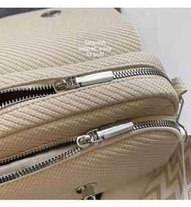 Detail of premium silver dual zippers and woven texture on beige square bag