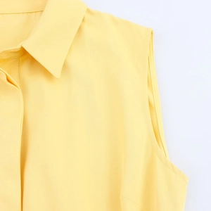 Detail of bright yellow sleeveless shirt collar showing twill fabric texture and stitching