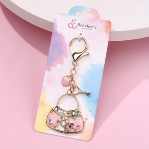 Pink rhinestone handbag keychain with heart charm on branded display card