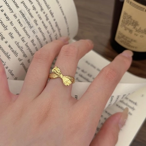 Detailed view of a gold bow ring with textured finish worn on hand for daily lifestyle