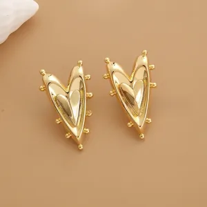 Close-up of gold heart stud earrings with unique studded edges and layered texture