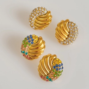 Detailed macro view of vintage gold earrings with colorful zircon and emerald stones