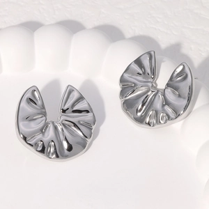 Macro shot of silver pleated fan-shaped stainless steel earrings on a cloud tray