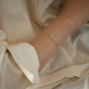 Close-up of 14K gold plated rose flower bracelet with purple zircon on a model's wrist