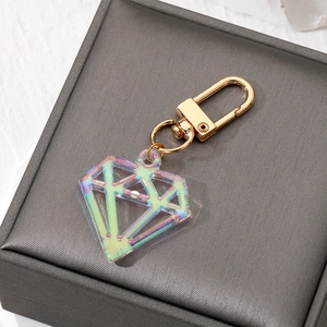Detail of diamond-shaped iridescent acrylic keychain with a gold metal hook on grey box