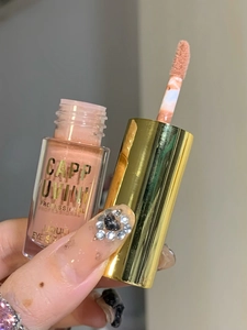 Close-up of pink liquid eye shadow with gold cap and professional applicator brush