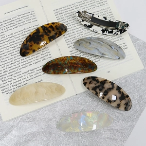 Elegant geometric acetate hair clip set in various patterns on a vintage book background