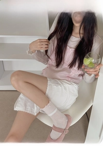 Dettaglio di calze rosa con fiocco abbinate a top in rete a pois e scarpe Mary Jane