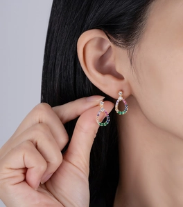 Detail of teardrop hollow stud earrings with colorful zircon stones on female model