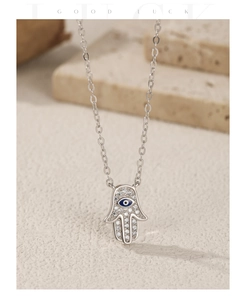 Macro shot of silver Hamsa necklace with sparkling zircons and blue evil eye detail