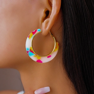 Close-up of C-shaped acetate hoop earrings with colorful terrazzo texture on model