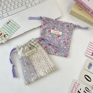 Pochettes à cordon en dentelle et fleurs lavande sur un bureau blanc épuré