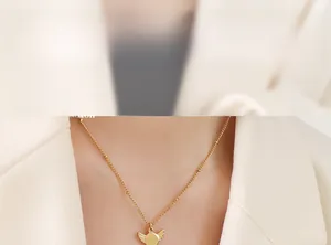 Detailed macro shot of gold-plated wing pendant necklace on model wearing white suit