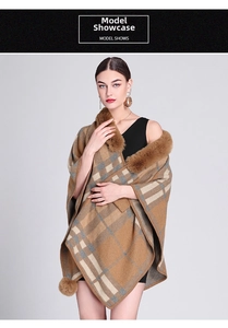 Detail of tan plaid poncho featuring faux rabbit fur trim and decorative pom-poms