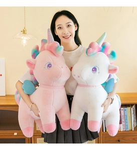 Close-up of soft pink and white plush unicorns with rainbow manes and shiny blue wings