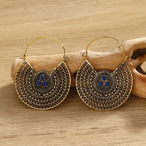 Macro detail of gold filigree hoop earrings with blue turquoise stones on wood