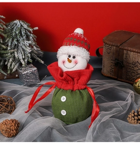 Detail of knitted snowman Christmas gift bag with drawstring and festive pine decor
