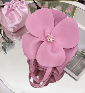 Top view of pink 3D flower tote bag with satin drawstring pouch on a mirror surface