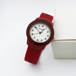 Detailed close-up of dark red silicone quartz watch with white dial on white gift box