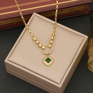 Detail of emerald green square pendant on a gold beaded chain jewelry piece