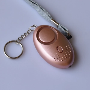 Detail view of rose gold personal safety alarm with metal keychain and grey woven lanyard