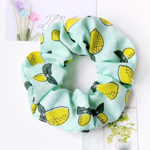 Close-up of mint green fabric scrunchie with yellow lemon patterns on white background