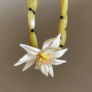 Détail macro du collier vintage français avec perles jaunes et pendentif fleur