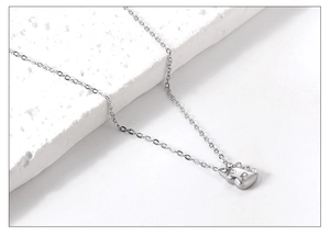 Gros plan du collier pendentif dinosaure argenté avec strass brillants sur fond mat