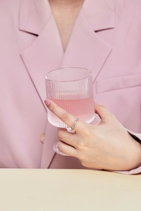 Close-up of a s925 silver ring with colorful zircons worn by a model holding a glass