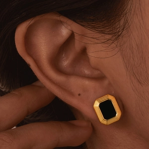 Close-up of vintage geometric gold earrings with black onyx stone inlay