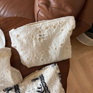 Detail of floral lace embroidery and Simple Wish logo on beige mesh cosmetic bag