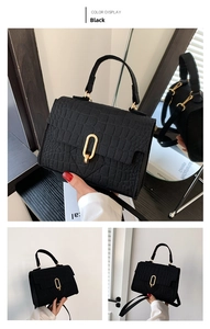 Detail of black crocodile pattern handbag with gold clasp and textured felt material