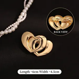 Detailed view of overlapping heart-shaped gold spring hair clip with smooth finish