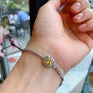 Close-up of a silver bracelet featuring a yellow square diamond worn on the wrist