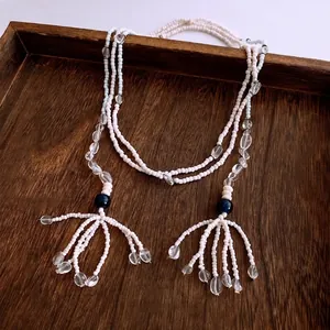 Ethic beaded tassel necklace with white seed beads and blue glass accents on wood