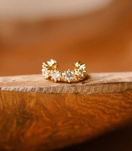 Macro view of gold ear cuff with white cubic zirconia stones on wooden surface