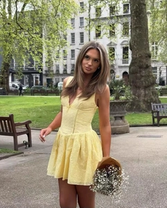 Détail de la robe courte en dentelle jaune avec broderie ajourée et taille cintrée