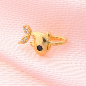 Close-up of golden whale ear cuff with tiny white diamonds on pink silk fabric